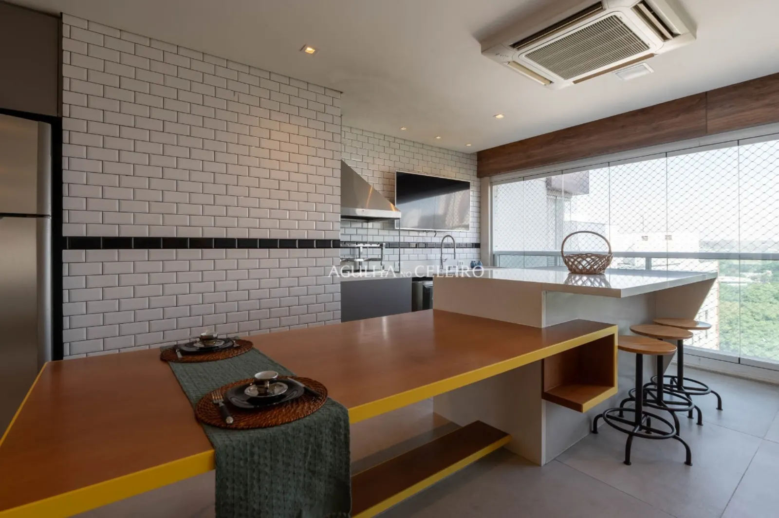 Varanda gourmet integrada com vista para o skyline de Pinheiros.
